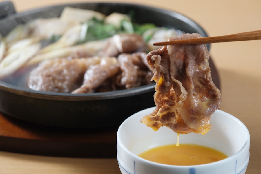 Eat sukiyaki by dipping it in raw egg